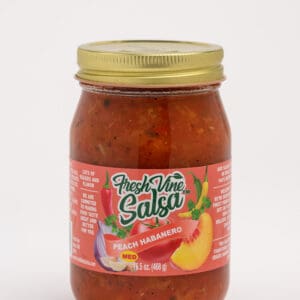 A jar of salsa with some fruit on it