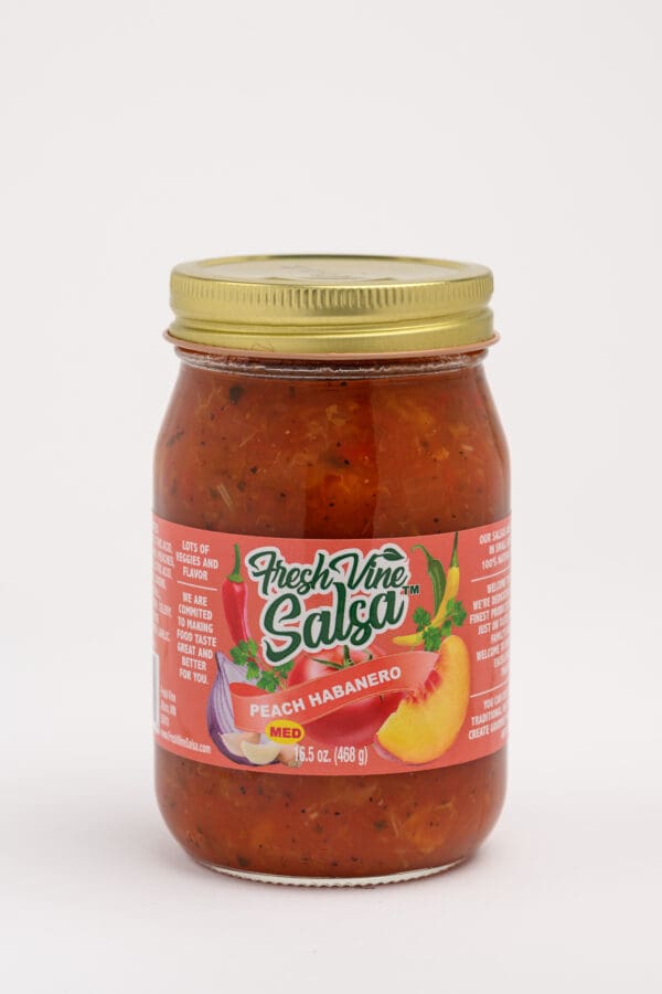 A jar of salsa with some fruit on it