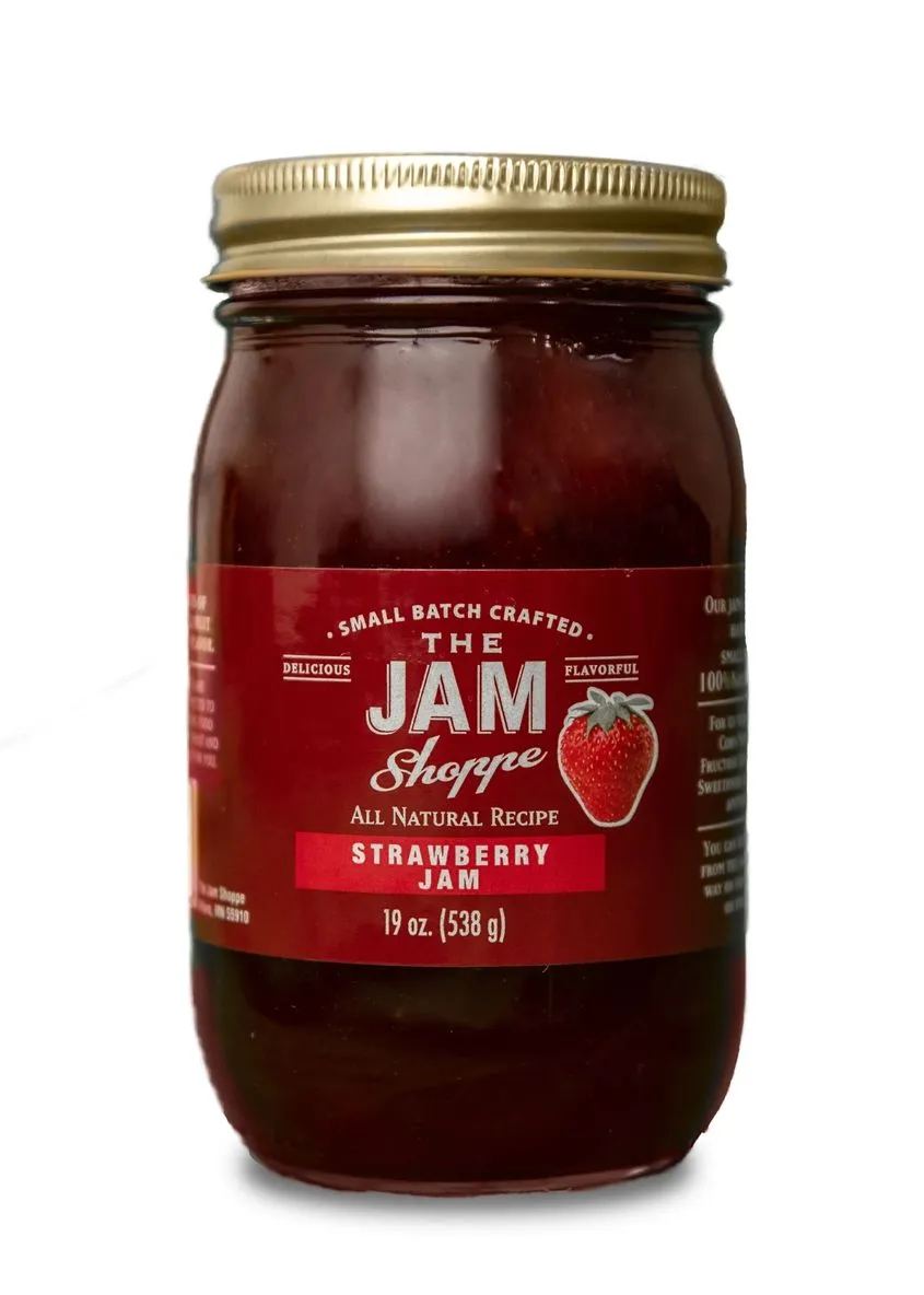 A jar of jam with the label " the jam shoppe strawberry jam ".